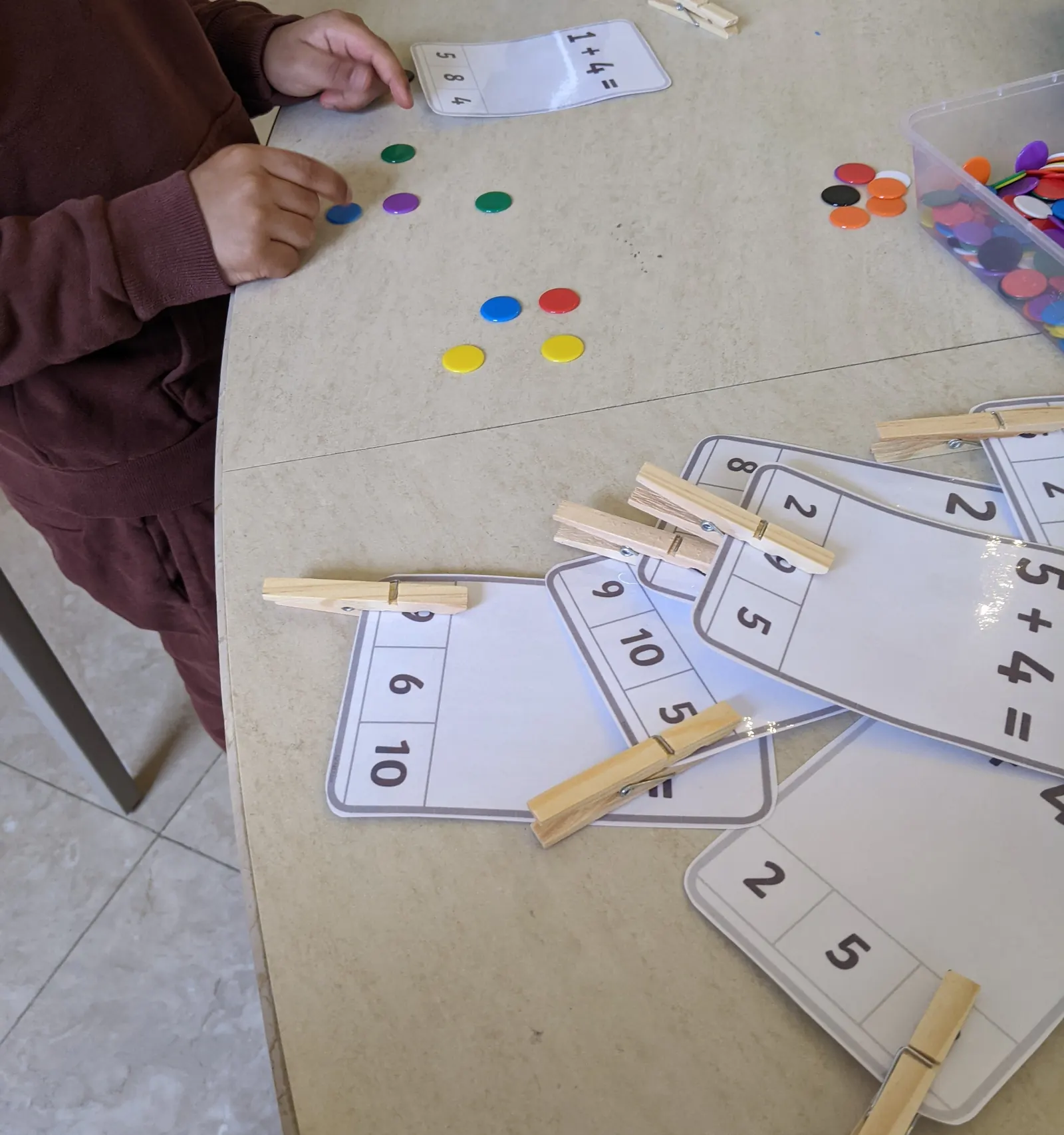 Number cards with wooden pegs and coloured counters for an addition activity